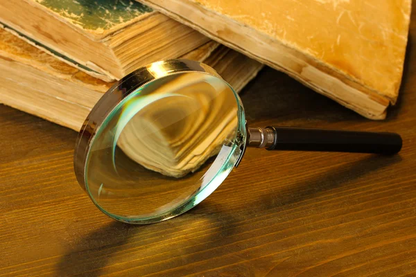 Magnifying glass and books on table — Stock Photo, Image