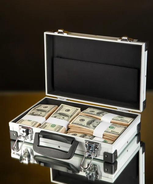 Maleta con billetes de 100 dólares sobre fondo de color oscuro — Foto de Stock