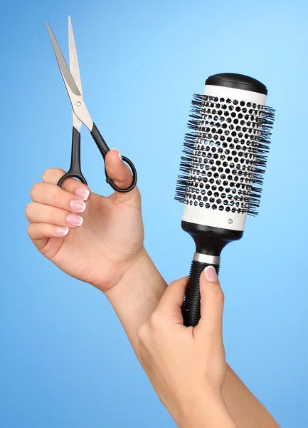 Kleur kam en schaar in vrouwelijke hand op kleur achtergrond — Stockfoto