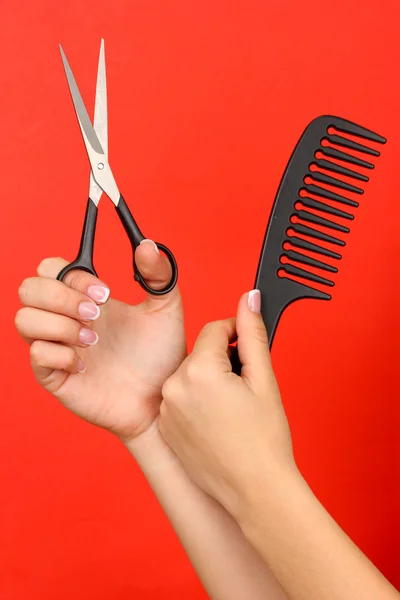 Color comb and scissors in female hand on color background — Stock Photo, Image