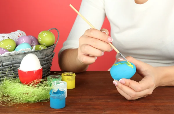 Mujer joven pintando huevos de Pascua, sobre fondo de color — Foto de Stock