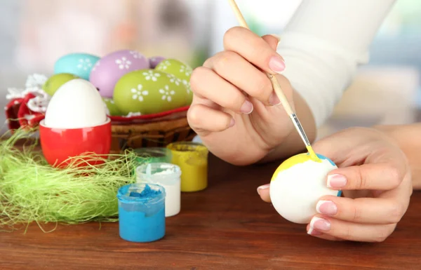 Jovem mulher pintando ovos de Páscoa, no fundo brilhante — Fotografia de Stock