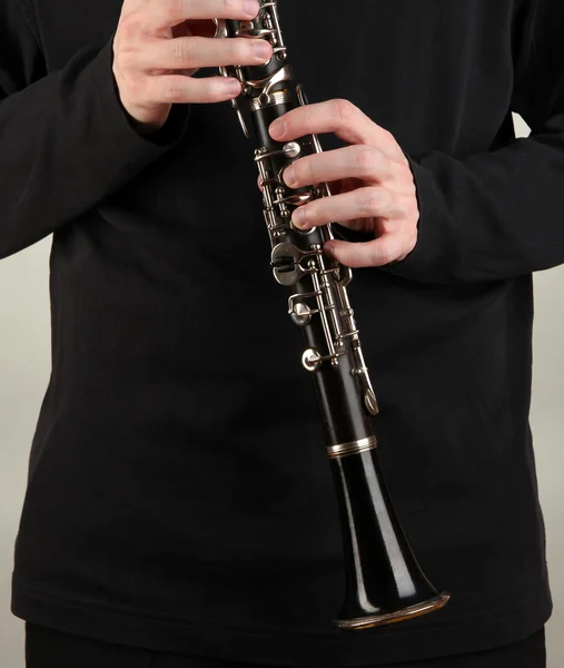 Musicista che suona il clarinetto su sfondo grigio — Foto Stock