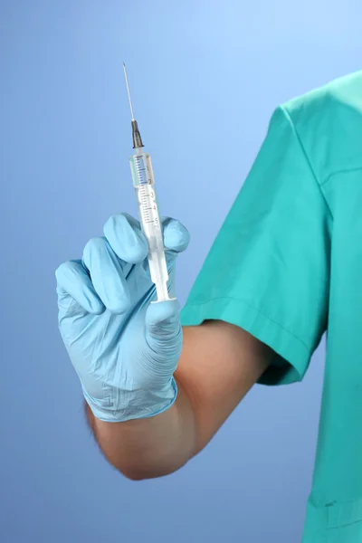 Médico com seringa sobre fundo azul — Fotografia de Stock