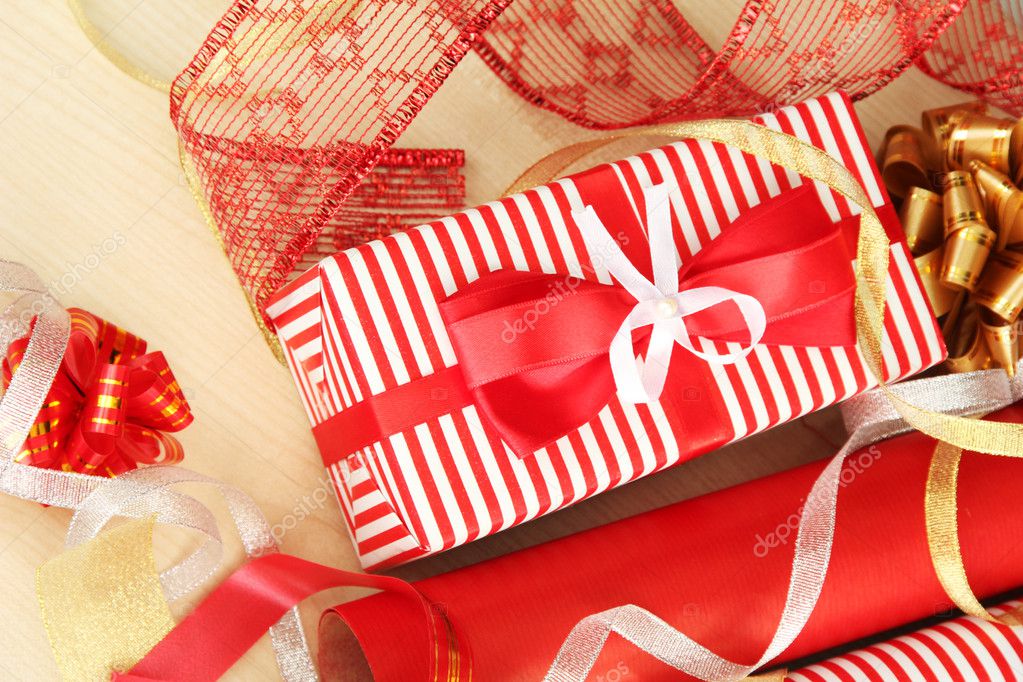 Rolls of Christmas wrapping paper with ribbons, bows on wooden
