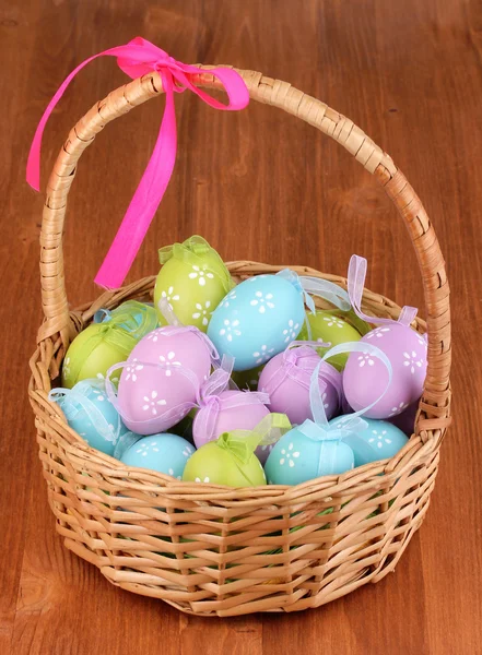 Ovos de Páscoa coloridos em cesta no fundo de madeira — Fotografia de Stock