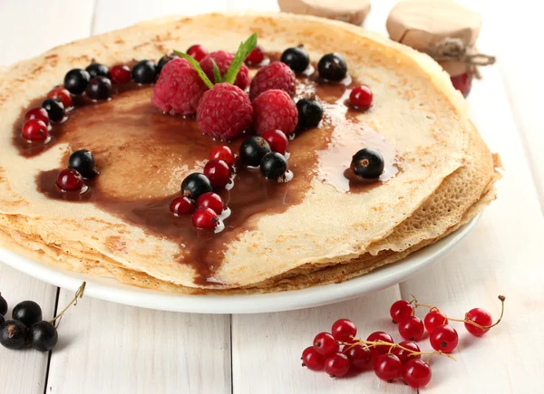 Вкусные блинчики с ягодами и джемом на тарелке на деревянном столе — стоковое фото