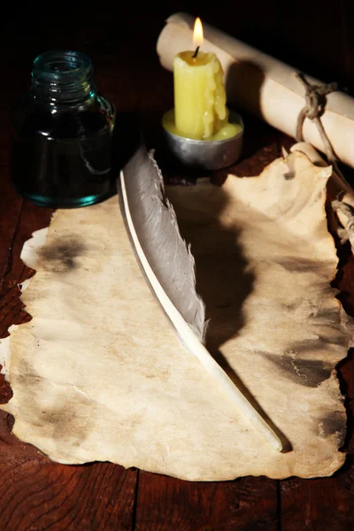 Papel velho com caneta de tinta perto da vela de iluminação na mesa de madeira — Fotografia de Stock