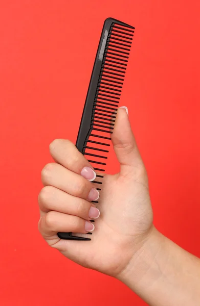 Black comb in female hand on color background — Stock Photo, Image