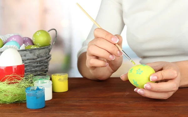 Mujer joven pintando huevos de Pascua, sobre fondo brillante —  Fotos de Stock