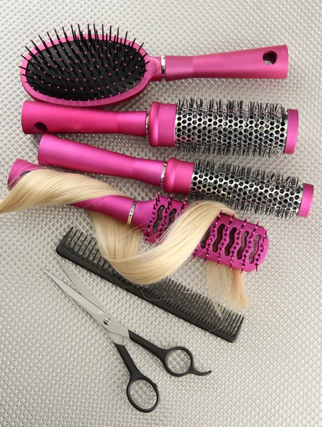 Comb brushes, hair and cutting shears, on grey background — Stock Photo, Image
