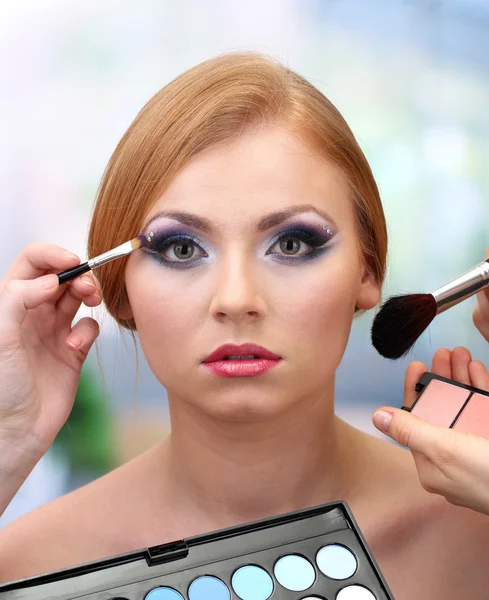 Portret van mooie jonge vrouw met het maken van make-up in beauty salon — Stockfoto