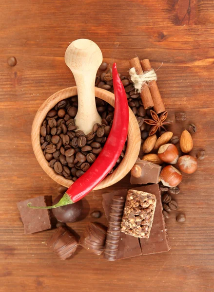 Chocolade snoepjes, mortel met koffiebonen op houten ondergrond — Stockfoto
