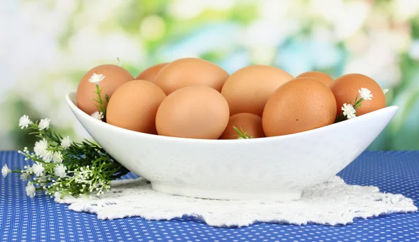 Яйца в белой чаше на голубой скатерти крупным планом — стоковое фото