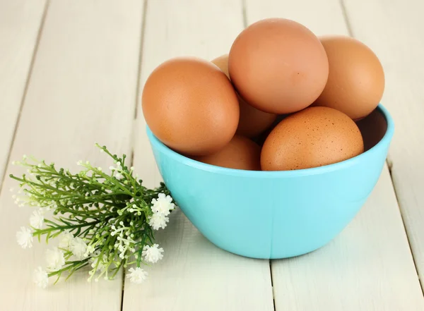 Ägg i blå skål på träbord närbild — Stockfoto