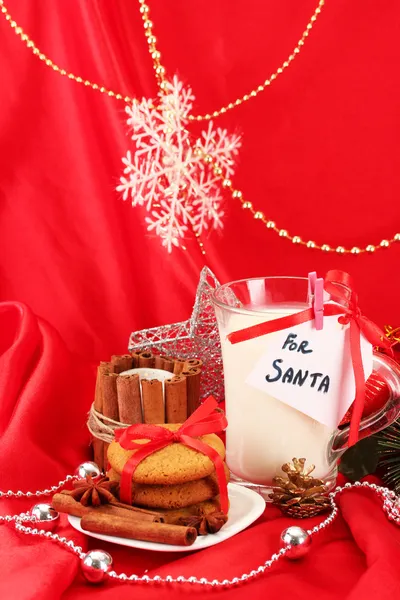 Galletas para Santa: Imagen conceptual de galletas de jengibre, leche y decoración navideña sobre fondo rojo — Foto de Stock