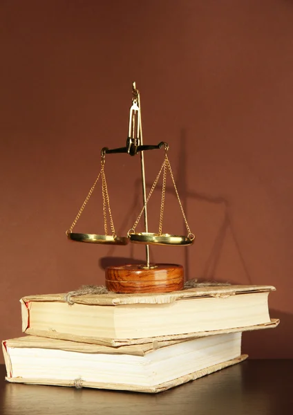 Gold scales of justice and books on brown background — Stock Photo, Image