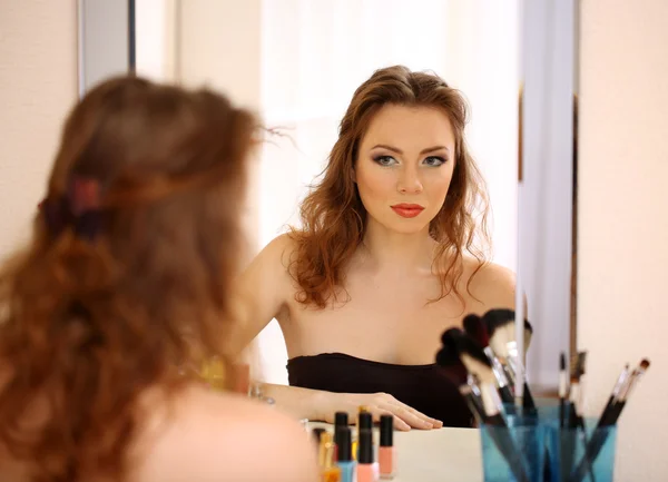 Joven hermosa mujer haciendo maquillaje cerca del espejo — Foto de Stock