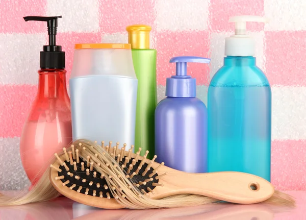 Comb brush with hair and cosmetic bottles in bathroom — Stock Photo, Image