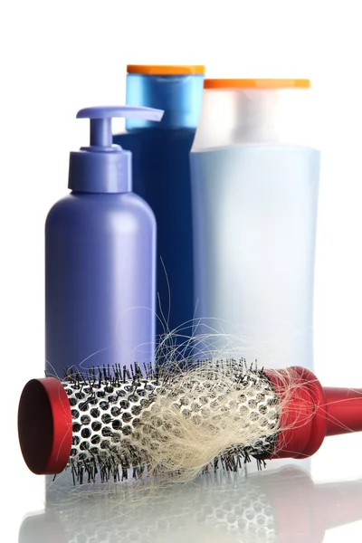 Escova de pente com cabelo perdido e garrafas de cosméticos, isolado em branco — Fotografia de Stock