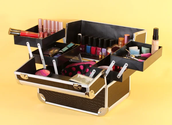 Open case with cosmetics on yellow background — Stock Photo, Image