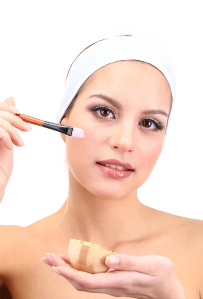 Mujer joven aplicando mascarilla facial de arcilla, aislada en blanco — Foto de Stock