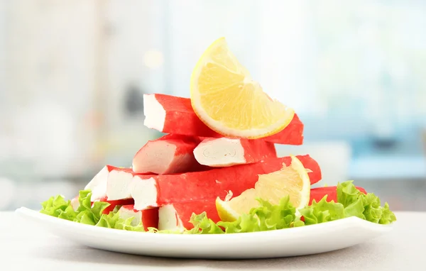 Krabbenstangen mit Salatblättern und Zitrone auf Teller, Nahaufnahme — Stockfoto