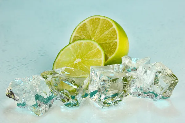 Ice cubes with lime on light blue background — Stock Photo, Image