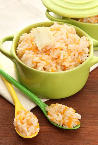 Taste rice porridge with pumpkin in saucepans on wooden background — Stock Photo, Image