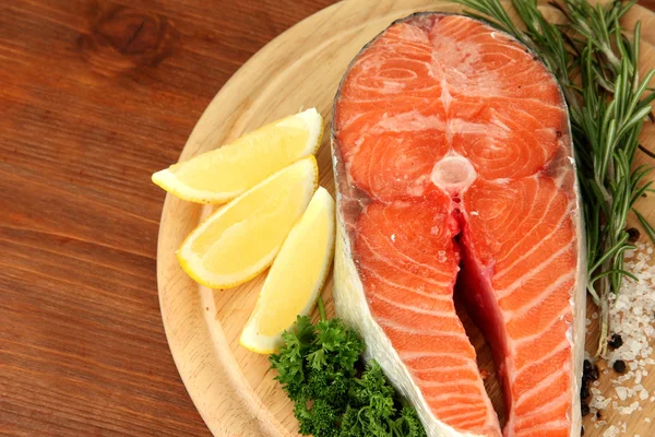 Fresh salmon steak on cutting board, on wooden background — Stock Photo, Image