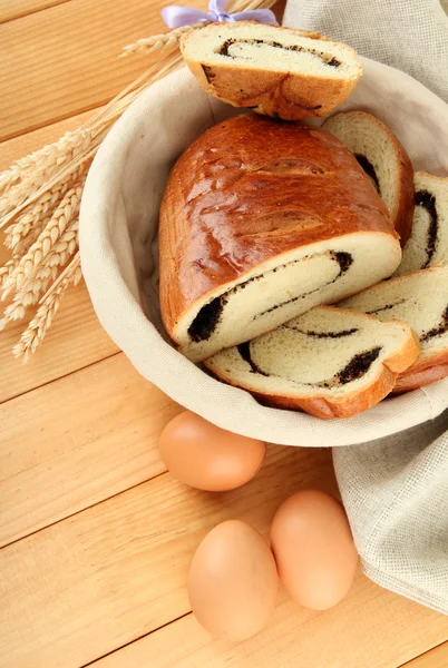 Loaf with poppy seeds in wicker basket, on wooden background — Stock Photo, Image