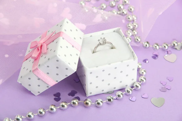 Piękne pudełko z obrączką na fioletowym tle — Zdjęcie stockowe
