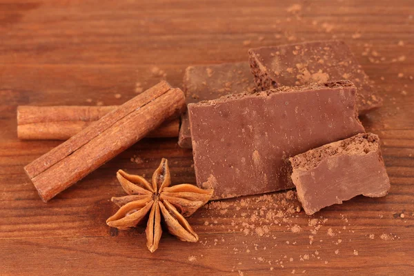 Chopped chocolate with cocoa, spices, on wooden background — Stock Photo, Image