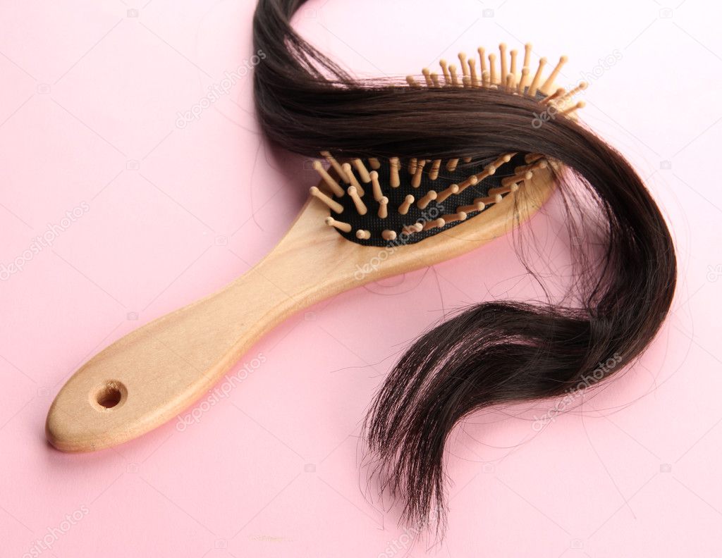 wooden comb brush with hair, on pink background