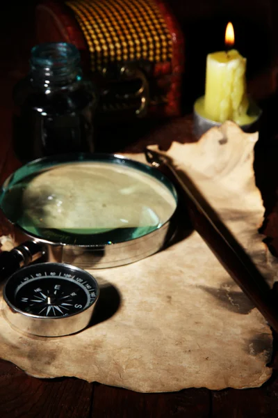 Papel viejo con pluma de tinta y lupa cerca de la vela de iluminación en la mesa de madera — Foto de Stock