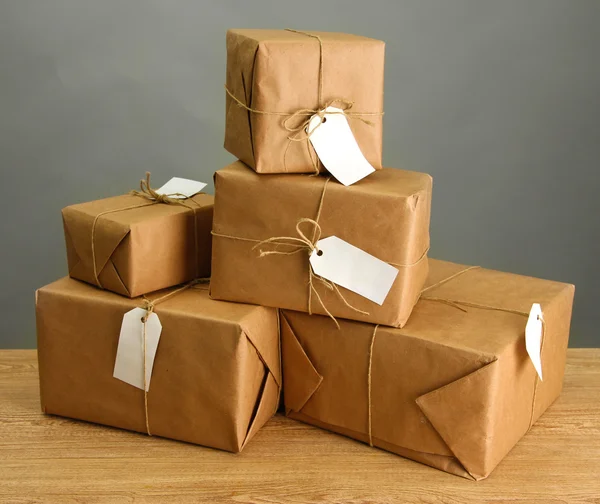 Cajas de paquetes con papel kraft, sobre mesa de madera sobre fondo gris —  Fotos de Stock