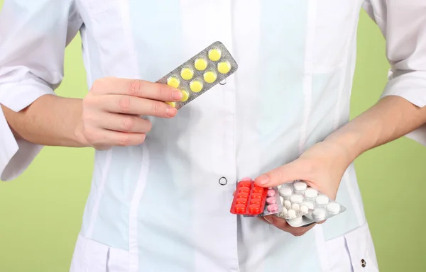 Close-up of female doctor hand holding pills, on color background — Stock Photo, Image