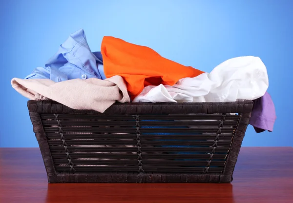 Bright clothes in laundry basket, on color background — Stock Photo, Image