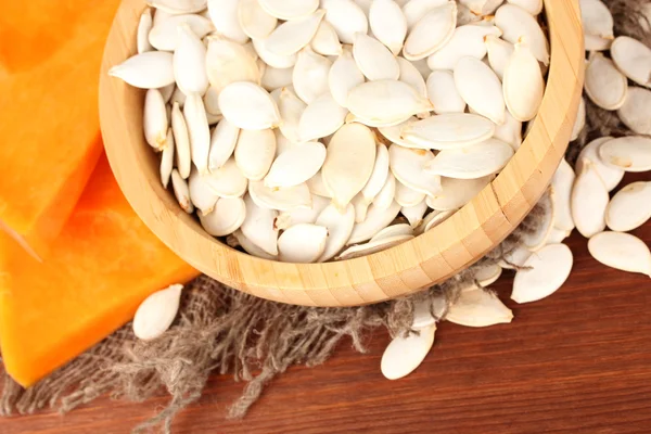 Pumpkin seeds in wooden bowl, on wooden background — Stock Photo, Image