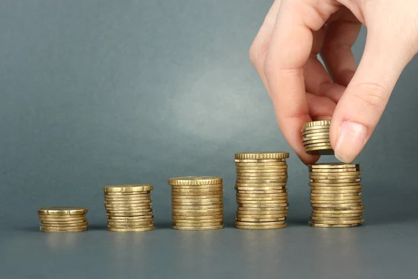 Mão segurando moedas em fundo cinza — Fotografia de Stock