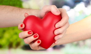 kadın ve adam ellerini, yeşil zemin üzerine kırmızı kalp