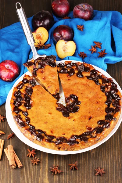 Torta saborosa na placa com ameixas na mesa de madeira — Fotografia de Stock