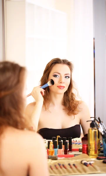 Jong mooi vrouw maken make-up in de buurt spiegel — Stockfoto