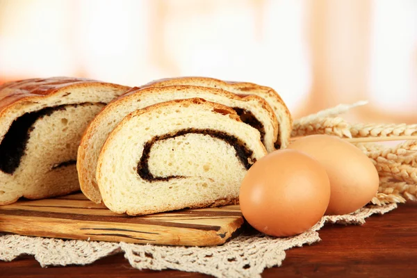 Brød med valmuefrø på skærebræt, på lys baggrund - Stock-foto