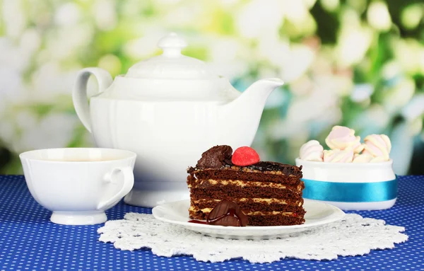 Tetera, taza de té y delicioso pastel sobre fondo natural —  Fotos de Stock
