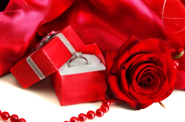 Hermosa caja con anillo de boda y rosa sobre fondo de seda roja — Foto de Stock