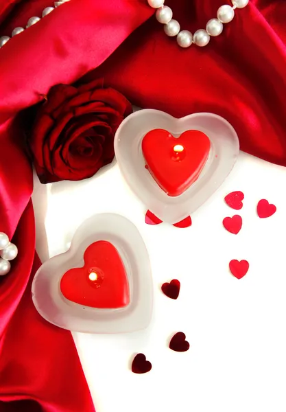 Mooie kaarsen en rose op rode zijde achtergrond — Stockfoto
