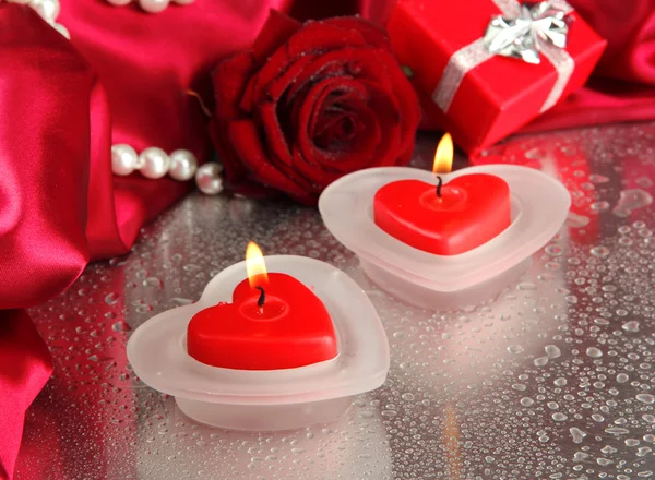 Piękne świece, mokre róża i czerwony jedwabiu szary tło — Zdjęcie stockowe