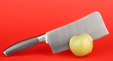 Yeşil elma ve kırmızı bir arka plan üzerinde bıçak