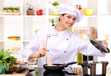 Young woman chef cooking in kitchen clipart